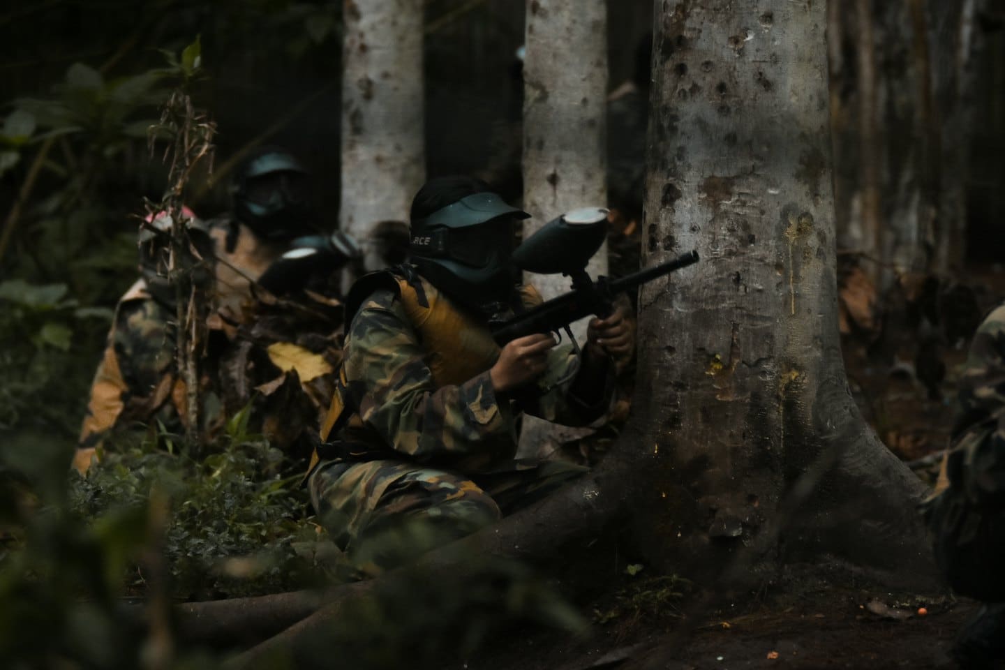 Due persone in mimetica giocano a paintball in una foresta.