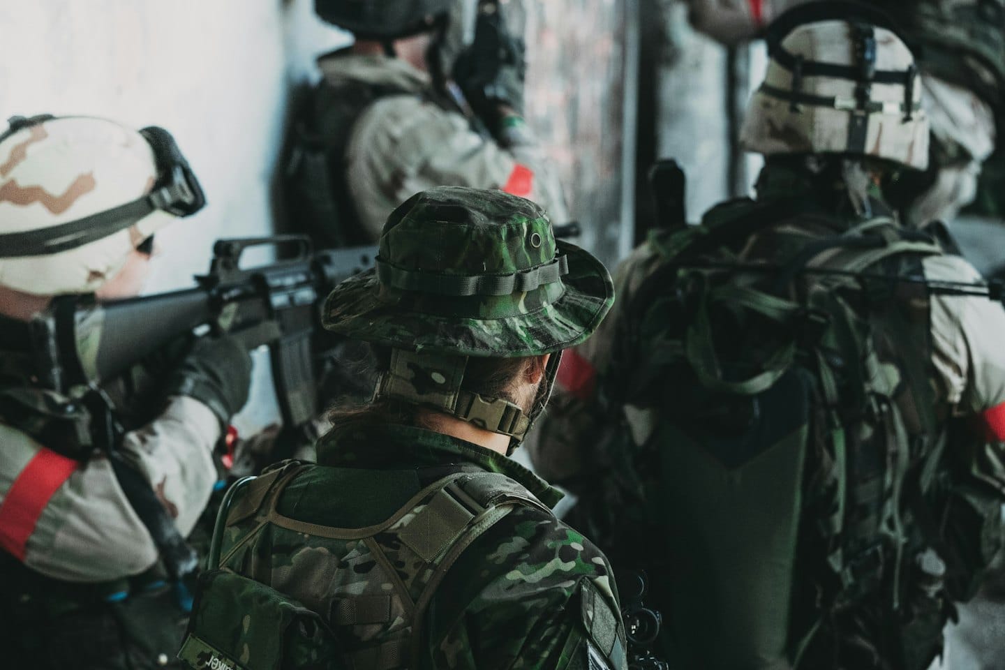 Uomini in tenuta tattica giocano ad airsoft in un'arena urbana.